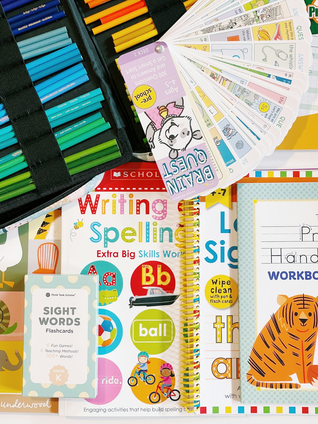 Educational workbooks and art supplies spread out on a desk.